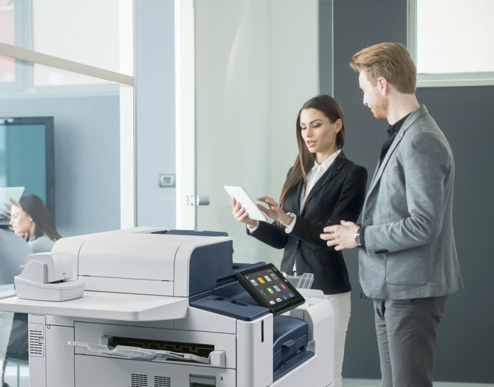 Stampante multifunzione moderna al centro di un ufficio ordinato con icone di sicurezza, risparmio e sostenibilità